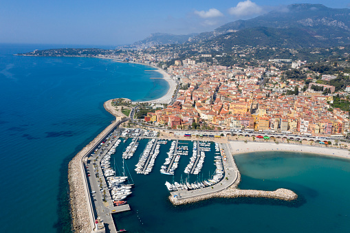 Rows of yachts in marina of Menton, old town is seen in the background, aerial view, Cote d'Azur, French Riviera, France, Europe.