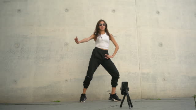Young influencer filming a dance video for social media with a smartphone on the street