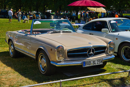 Baden-Baden, Germany - 10 July 2022: beige ivory Mercedes-Benz W113 230 SL Pagoda cabrio roadster 1966 is parked in Kurpark in Baden-Baden at the exhibition of old cars \