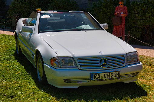 Baden-Baden, Germany - 10 July 2022: white Mercedes-Benz R129 SL 1989 cabrio roadster is parked in Kurpark in Baden-Baden at the exhibition of old cars \