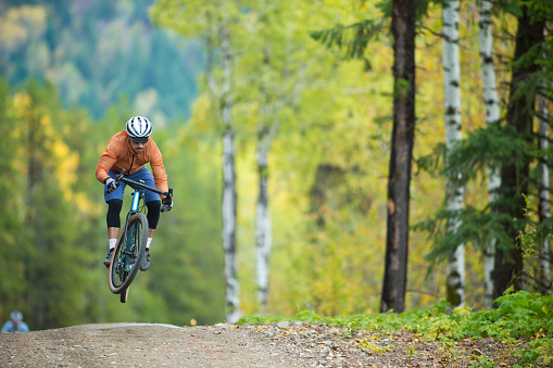 A man catches some air while riding his gravel bicycle on a country road. Gravel bicycles are similar to cyclo-cross bikes but have oversized tires for riding on rough terrain.