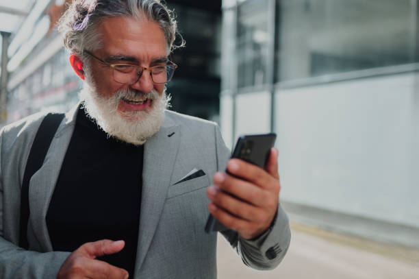istock Senior business man standing outside while using smartphone 1441035347