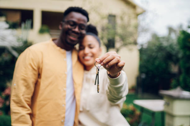 multiracial couple holding keys and standing outside their new home - garden key imagens e fotografias de stock