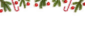 Christmas border with fir branches, candy cane and red baubles isolated on a white background. Banner. New Year frame. Copy space, template. Top view, flat lay.