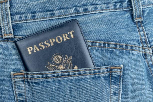 CLOSE UP OF USA PASSPORT IN BLUE JEANS POCKET. TOURIST AND TRAVELER CONCEPT FROM UNITED STATES OF AMERICA. CLOSE UP OF USA PASSPORT IN BLUE JEANS POCKET. TOURIST AND TRAVELER CONCEPT FROM UNITED STATES OF AMERICA. jeans denim passport pocket stock pictures, royalty-free photos & images