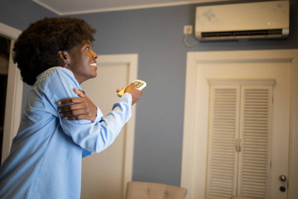 istock Woman turning on air conditioner 1441042391