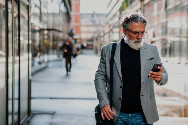 istock Senior businessman standing outside and using smartphone 1441043153