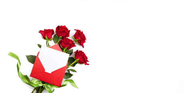 un mazzo di rose rosse, una busta rossa con un pezzo di carta vuoto per le congratulazioni o una dichiarazione d'amore su uno sfondo bianco isolato. - rose valentines day bouquet red foto e immagini stock