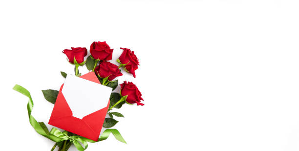 um buquê de rosas vermelhas, um envelope vermelho com um pedaço de papel vazio para parabéns ou uma declaração de amor em um fundo branco isolado. - rose valentines day bouquet red - fotografias e filmes do acervo