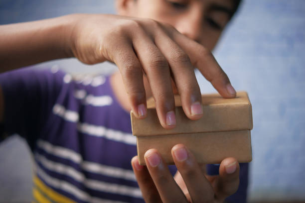 nastolatek otwiera puste małe pudełko z prezentami - brown boy zdjęcia i obrazy z banku zdjęć