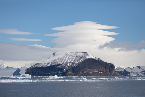 Lenticular clouds form over a mountain on the Antarctic Peninsula.