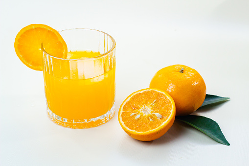 Glass of fresh orange juice on white table.