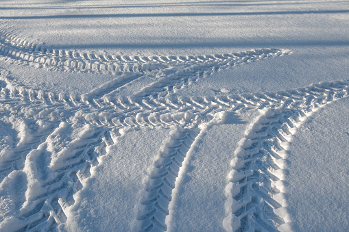 Traces of a wheeled tractor in the snow in the field. Winter Snow Patterns