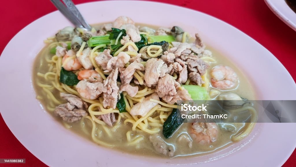 Authentic Penang fried hokkien mee or noodle served in plate Authentic Penang fried hokkien mee or noodle served in plate on red table top Asia Stock Photo