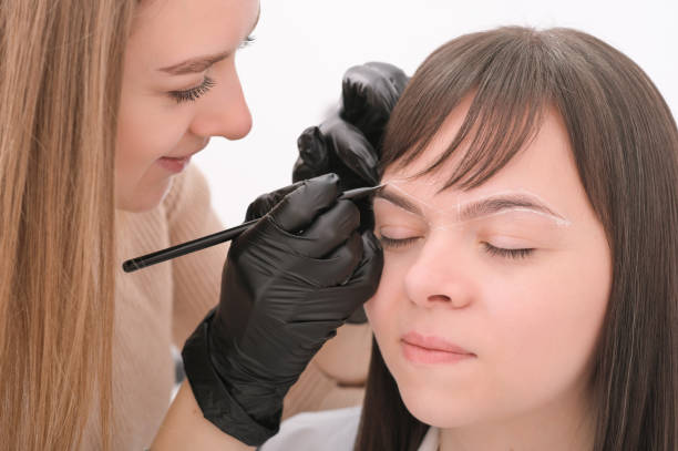 istock Brow marking and measuring before microblading or henna tattoo close-up. White brow paste, threading. young beautician woman professional with client. 1441080620