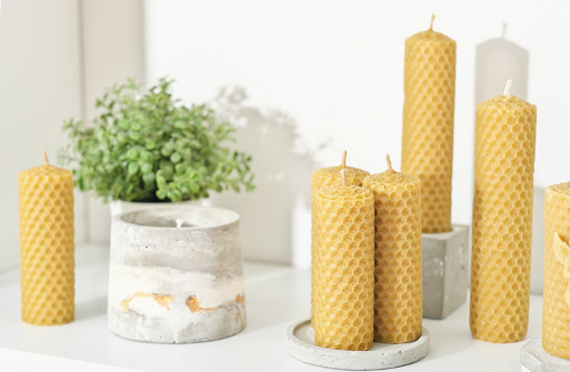 beeswax candles for home decor on a shelf with concrete flower pots. hand made candles made of natural wax with honey fragrance