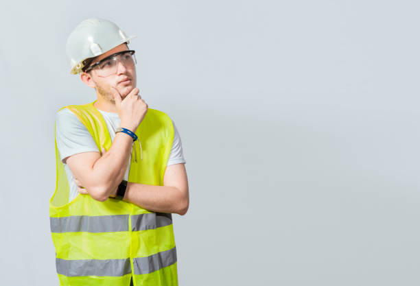 istock A pensive engineer on white background. Concept of a meditative engineer solated. Pensive builder man with hand on chin, Portrait of young builder thinking with hand on chin isolated 1441095433