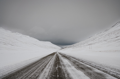 Middle of snow covered icelandic Country Road in Winter. Highway through the Northern Icelandic Mountain Range close to the City of Akureyri under snowy overcast sky, Northern Iceland, Iceland, Northern Europe.