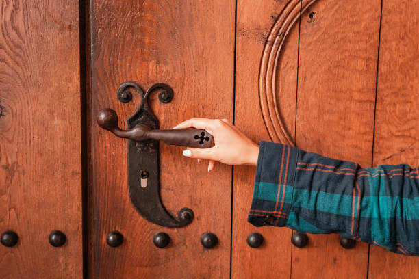 tourist girl enters the wooden door of a small chapel or church in the old town square. Take to religion concept stock photo