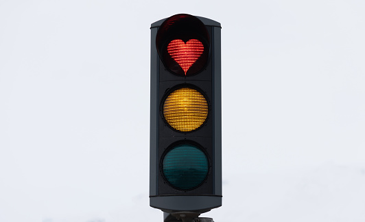 Icelandic Traffic Light Detail with a Heart Shaped Red Light against overcast white winter sky. Heart Shaped Love Symbol in Red Stop Light inside a typical City Traffic Light in the City of Akureyri, Northern Iceland. Akureyri, Iceland, Northern Europe in Wintertime.