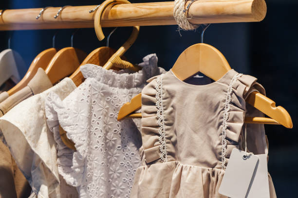 vestidos infantis na loja em cabides. alfaiataria para os mais novos - child clothing arrangement hanger - fotografias e filmes do acervo
