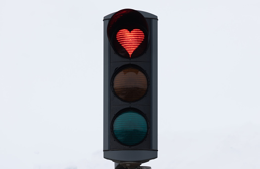 Icelandic Traffic Light Detail with a Heart Shaped Red Light against overcast white winter sky. Heart Shaped Love Symbol in Red Stop Light inside a typical City Traffic Light in the City of Akureyri, Northern Iceland. Akureyri, Iceland, Northern Europe in Wintertime.