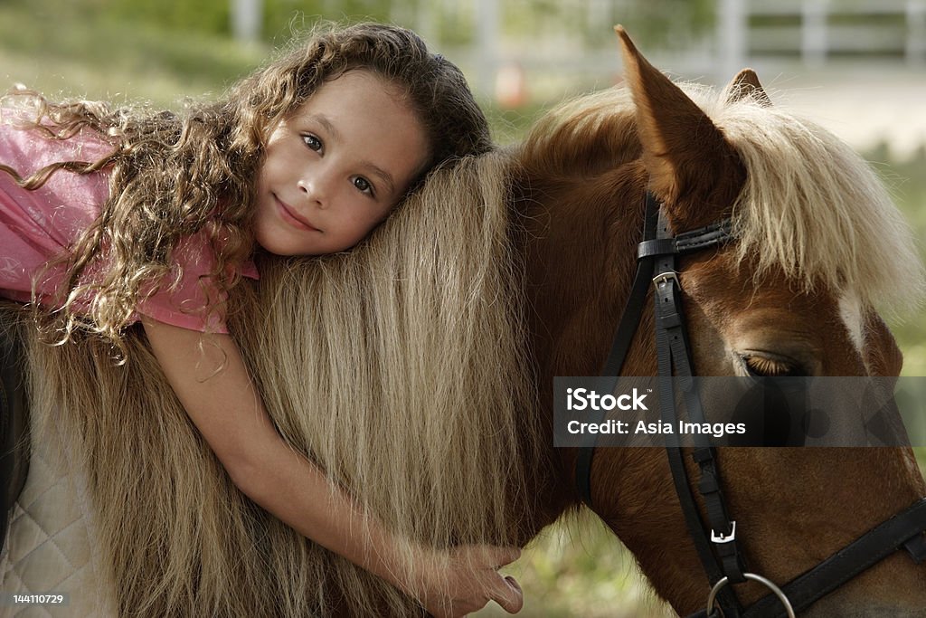 Giovane ragazza abbracciare pony - Foto stock royalty-free di Bambino