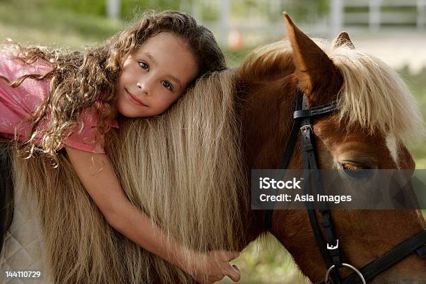 Giovane Ragazza Abbracciare Pony - Fotografie stock e altre immagini di Bambino - Bambino, Bambine femmine, Cavallo - Equino