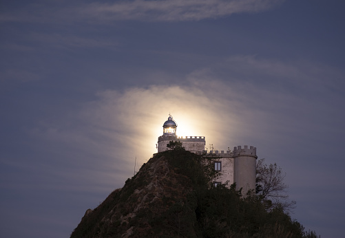 Full moon behind the La Plata lighthouse at sunset in Euskadi