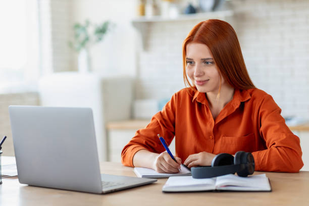 istock Concentrated young caucasian woman student using laptop computer for online education, watching the webinar, taking notes in notebook, studying, distance learning at home 1441116799