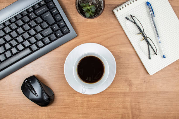 Cup of coffee on desktop with computer and notepad, top view, flat lay
