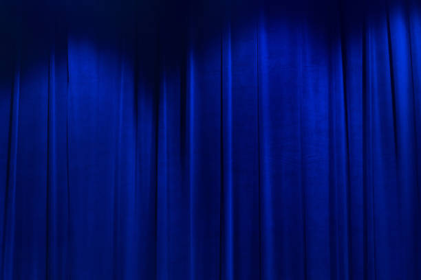istock Blue brightly movie theater curtains with spotlight. 1441119037
