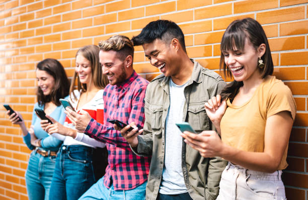 Multicultural friends using smart phones at university college break - Milenial students addicted by mobile smartphone - Tech life style concept with always connected millennials - Vivid filter stock photo