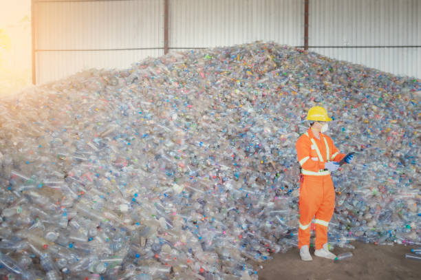 istock Workers in landfill dumping, Garbage engineer, recycling, wearing a safety suit standing in the recycling center have a plastic bottle for recycling in the factory 1441119941