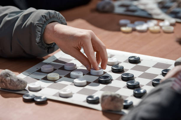 istock Outdoor draughts competition on paper checkerboard on table, close up players hands 1441120268