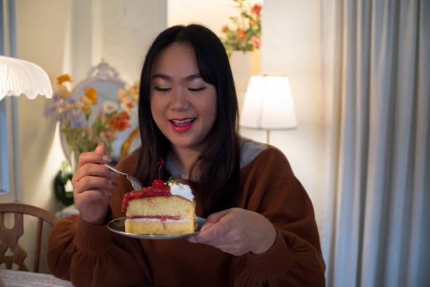 istock Women eating cake at home with happy face expression. 1441121316