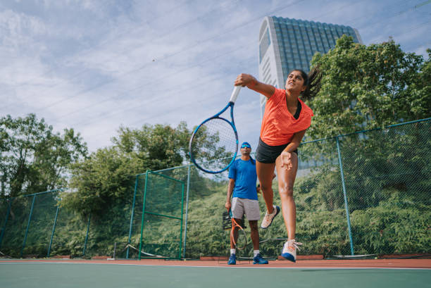 sport training Asian Indian female Tennis Player Serving The Ball practicing at tennis court with coach guidance sport training Asian Indian female Tennis Player Serving The Ball practicing at tennis court with coach guidance tennis coach stock pictures, royalty-free photos & images