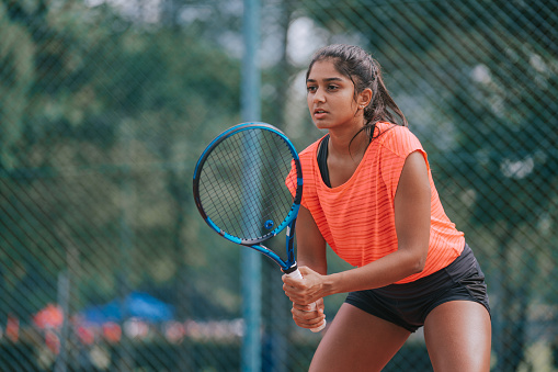 Asian Indian female Tennis Player practicing at tennis court during weekend morning