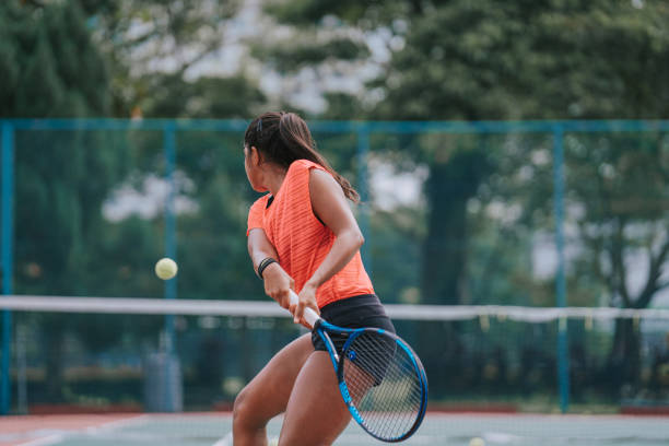 Asian Indian female Tennis Player Serving The Ball practicing at tennis court with coach guidance Asian Indian female Tennis Player Serving The Ball practicing at tennis court with coach guidance backhand stroke stock pictures, royalty-free photos & images