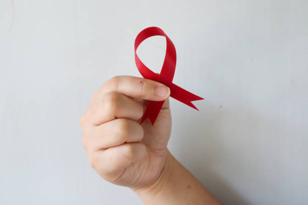 close-up view of hand holding red ribbon showing hiv disease symbol with copy space. awareness concept. healthcare concept. world aids day. - world aids day stok fotoğraflar ve resimler