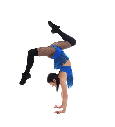 Beautiful cheerleader in costume doing handstand on white background