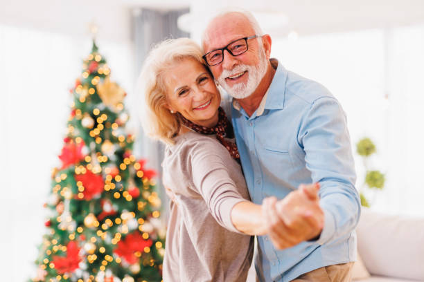 Senior couple hugging and dancing while celebrating Christmas at home stock photo