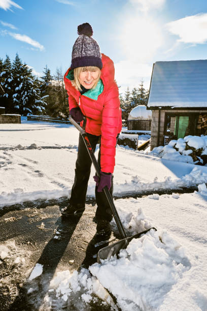 istock Woman clearing snow from her front yard using a snow shovel 1441126521