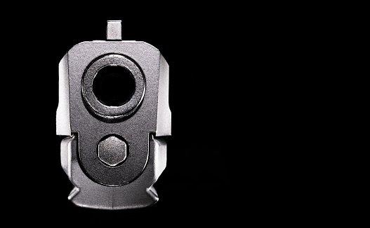 Pistol pointed directly at the viewer on a black backround with room for text