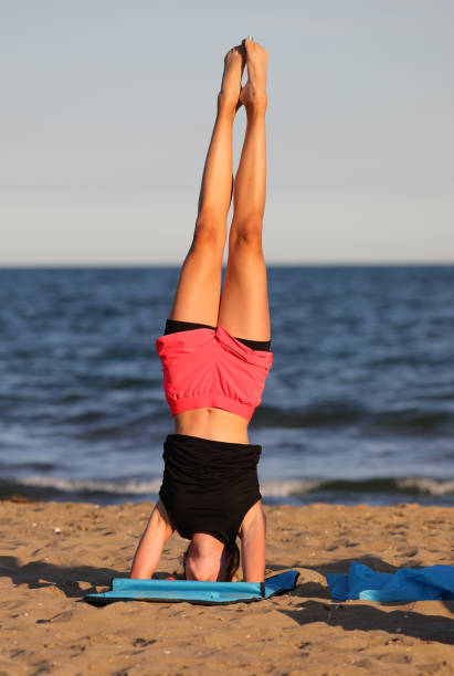 istock young girl stays balanced on the gym mat while doing exercises on the beach 1441133190