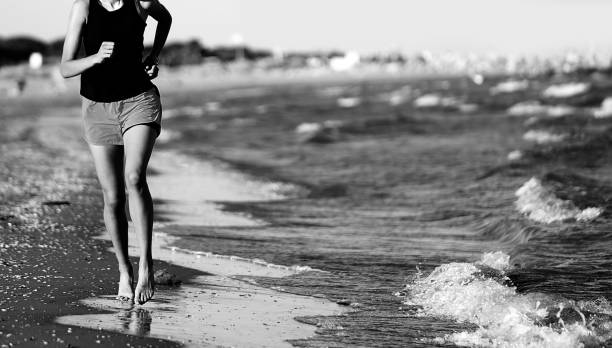 girl jogging running on the seashore in summer with black and white effect