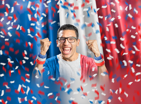 French soccer fan celebrating with national flag of France with confetti