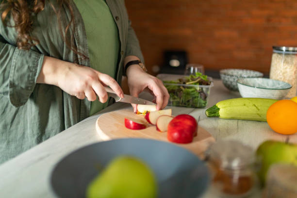 istock Woman cutting apple while preparing healthy breakfast at home 1441135491