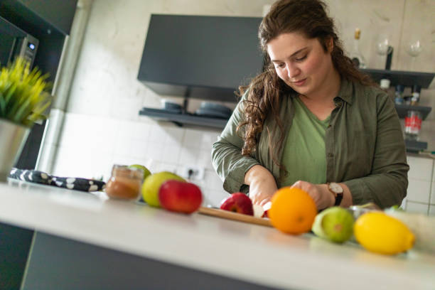 Woman cutting apple while preparing healthy breakfast at home stock photo