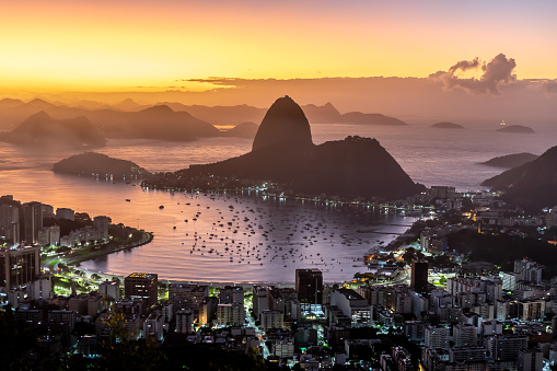 Aerial view of the Sugarloaf mountain touching the waters of the Guanabara bay, Rio de Janeiro, under the pink skies of a rising sun